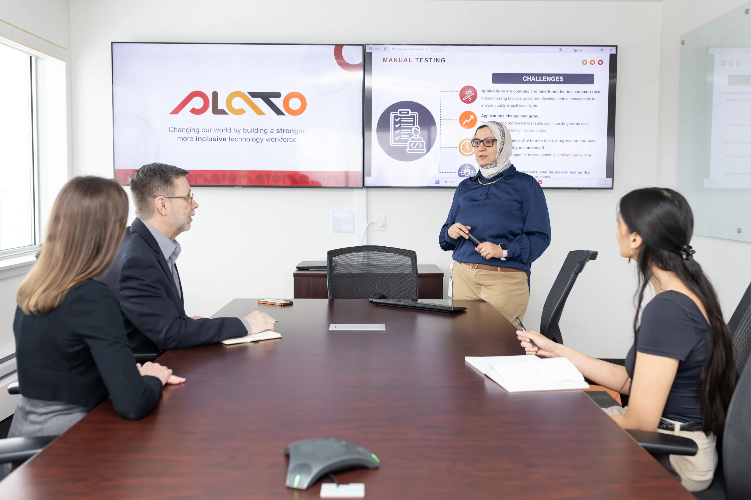 Automation_Experts_TestingServices.jpg Behind the back viewpoint, a woman stands presenting to others seated around a boardroom table.